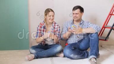 一对幸福的年轻夫妇坐在<strong>正在装修</strong>的新房子的地板上放松